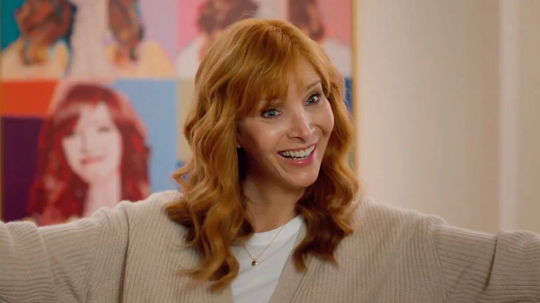 Lisa Kudrow as Valerie Cherish wearing a white shirt and beige sweater while smiling with her arms outstretched in a scene from "The Comeback."