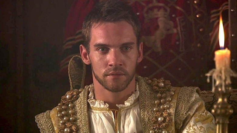 King Henry Vii in a gold outfit sitting beside a candle in The Tudors