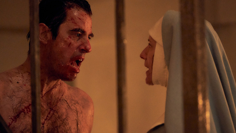 A shirtless Dracula covered in blood and facing Sister Agatha on Dracula