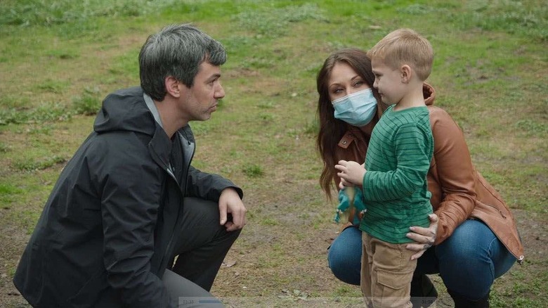 Nathan Fielder kneeling in front of Remy, a child actor, who is standing next to his mom in The Rehearsal episode "Pretend Daddy"