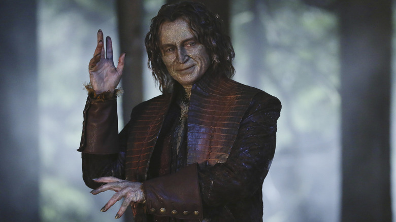 Rumplestiltskin smirking with one hand raised in Once Upon a Time.
