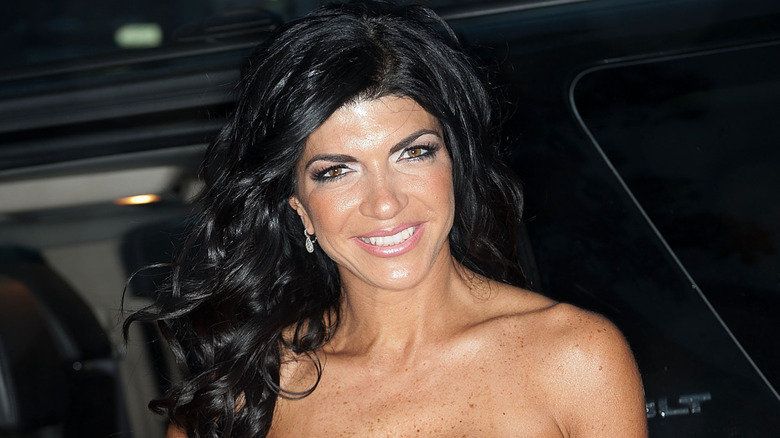 Teresa Giudice smiling while posing after stepping out of a car