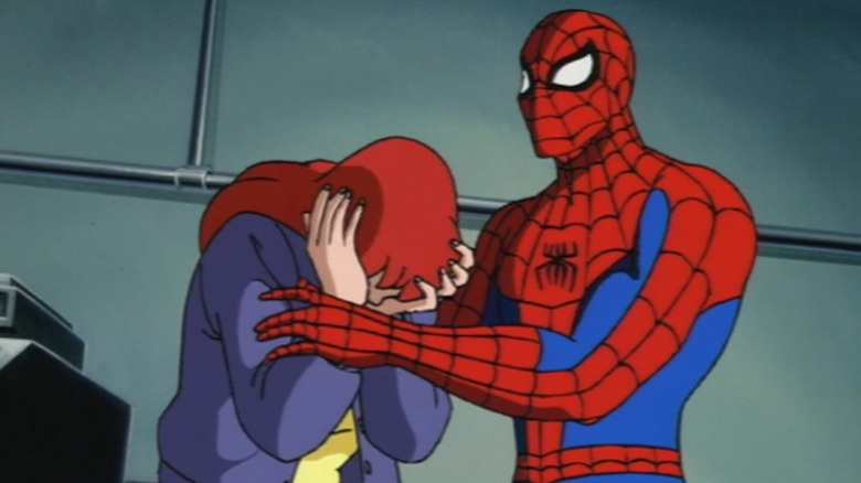 Spider-Man wearing a red and blue costume, with black-rimmed white lenses and a black spider logo on his chest. He is comforting Mary Jane, who has red hair and her head in her hands, she is wearing a purple jacket.