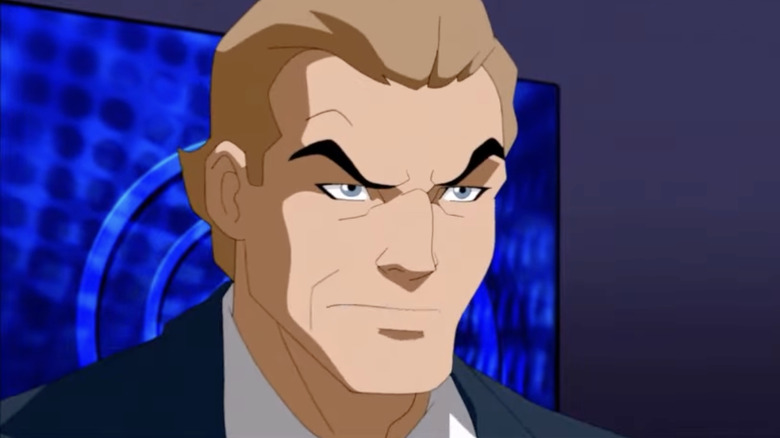 G. Gordon Godfrey, with slicked-back light brown hair, is scowling, wearing a black suit, with a blue TV screen behind him.