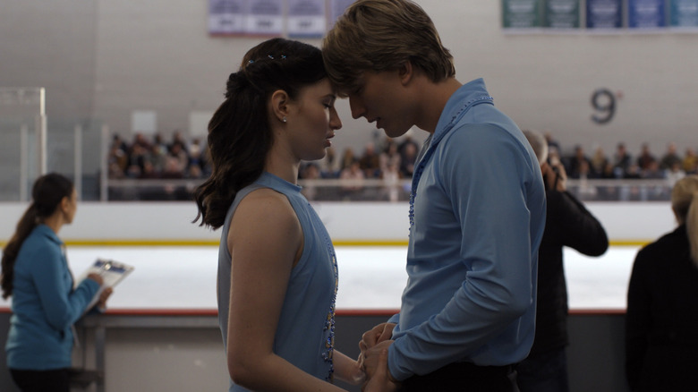 Adriana Russo (Madelyn Keys) and Brayden Elliot (Cale Ambrozic) holding hands with their foreheads touching each other in front of an ice skating rink in a scene from "Finding Her Edge."