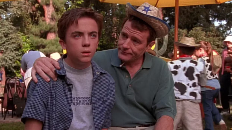 Hal wraps his arm around his dumbfounded son Malcolm while wearing a small cowboy hat in "Malcolm in the Middle"