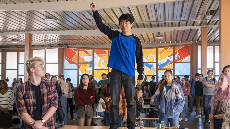 Jin Wang stands on a school cafeteria table in "American Born Chinese" (2023)