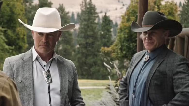 The Beck brothers. On the left is Neal McDonagh as Malcolm Beck wearing a light gray suit jacket, white shirt, a black bolo neck tie with a silver buckle and a white cowboy hat. On the right is Terry Serpico as Teal Beck wearing a dark gray suit jacket, a black bolo neck tie with a silver buckle and a dark gray shirt.