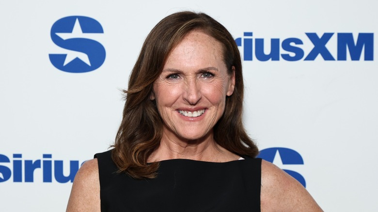Molly Shannon wearing a black dress and smiling at the camera.