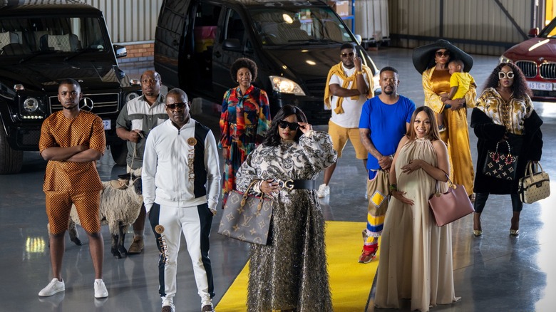 The cast of "How to Ruin Christmas" pose together in colourful outfits varying in style from classy to informal.