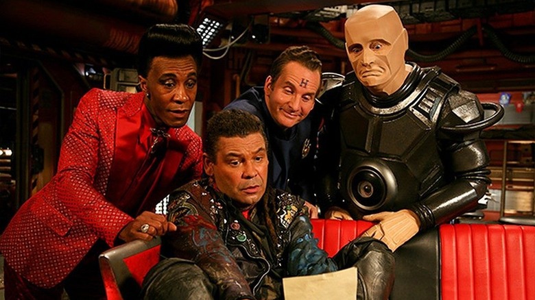 The Cat, Lister, Rimmer and Kryten gather to read a letter on Red Dwarf.