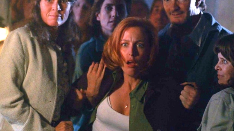Scully looking horrified among a group of people