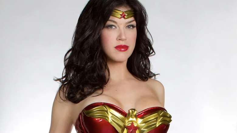 Adrianne Palicki as Wonder Woman with long dark hair. she's wearing a gold tiara on her forehead with a red star in the middle. She's also wearing a bright red corset with a golden eagle with a red star in the middle of its chest.