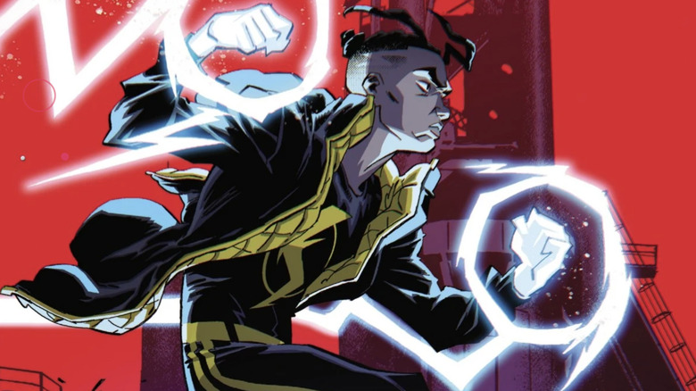 Static wearing a long black coat with a yellow padded lining. There is a lightning bolt symbol on his chest. He has white energy buzzing around his fists, which are also glowing with energy.