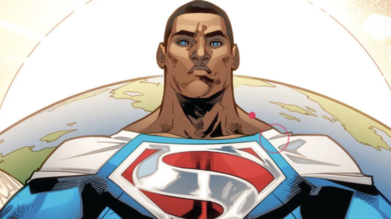 Val-Zod with short black hair, a white cape, and a blue superhero suit. There is a silver and red "S" symbol on his chest. The Earth is behind him.