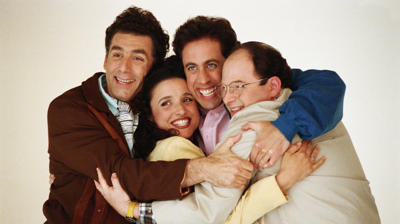 The cast of "Seinfeld" hugging and smiling at camera.