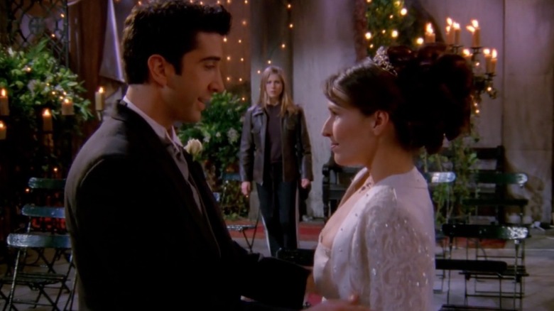 Ross (David Schwimmer) and Emily (Helen Baxendale) facing each other at their wedding with Rachel (Jennifer Aniston) stood in the background between them in Friends (1998)