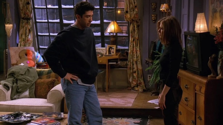 Ross in the apartment with his hands on his hips stood facing Rachel in Friends (1997)