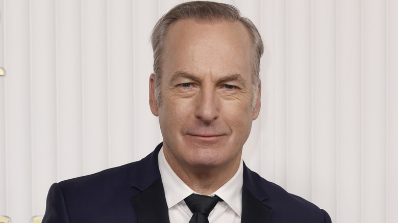 Bob Odenkirk in a black and white suit in front of a white background