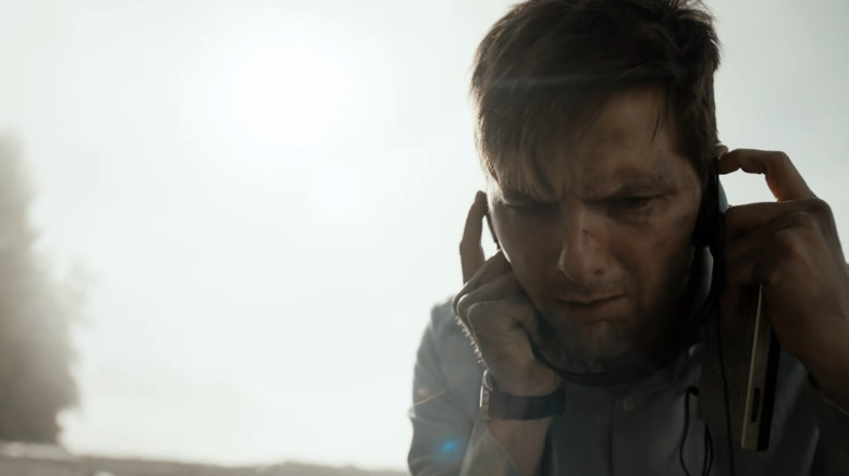 Justin Sanderson holding his fingers in his ears as he tries to hear something while standing on a beach in The Twilight Zone (2019)