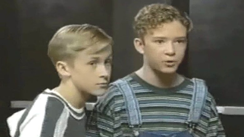 Young Ryan Gosling and Justin Timberlake in '90s clothing, with Timberlake wearing striped overalls and talking while Gosling looks on beside him in "The All-New Mickey Mouse Club."