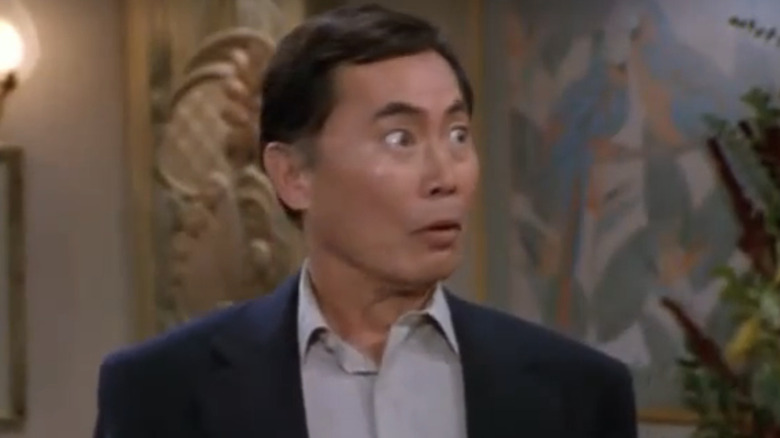 George Takei looking shocked in a hotel lobby in 3rd Rock From the Sun