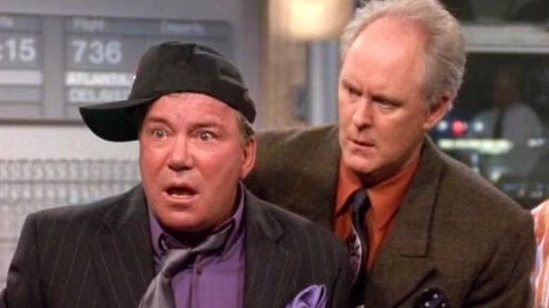 The Big Giant Head wearing a disheveled suit and a sideways cap while Dick Solomon looks over his shoulder in 3rd Rock From the Sun