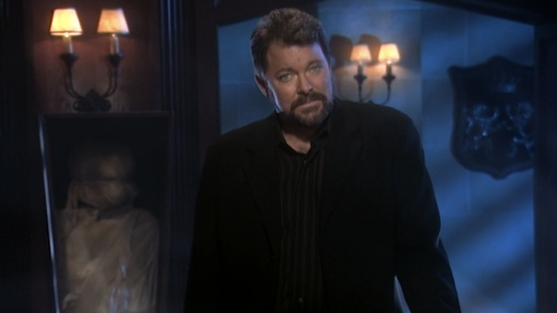 Jonathan Frakes standing in a candlelit room next to a fake mummy in a stand-up box while hosting Beyond Belief: Fact or Fiction