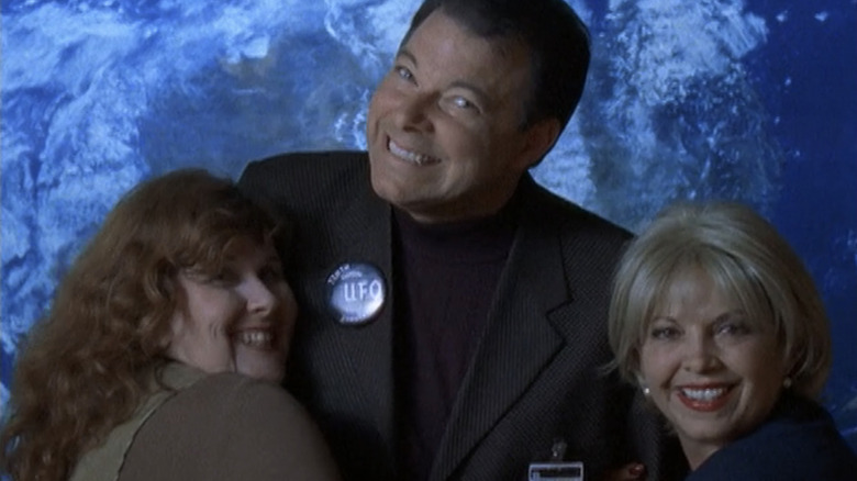 Jonathan Frakes playing himself and posing with two women while attending the UFO convention in Roswell