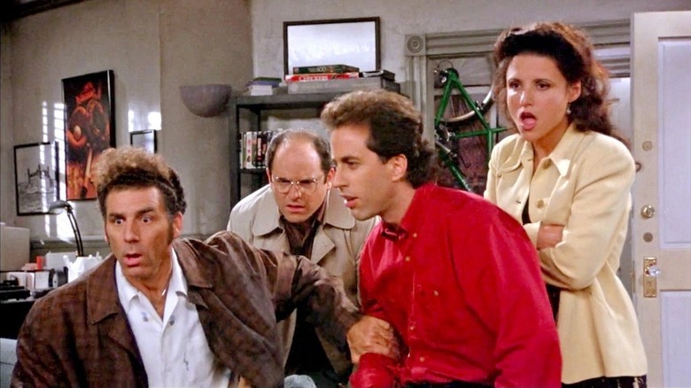 Kramer, George Costanza, Jerry Seinfeld, and Elaine Benes looking at something shocked in Jerry's living room in Seinfeld