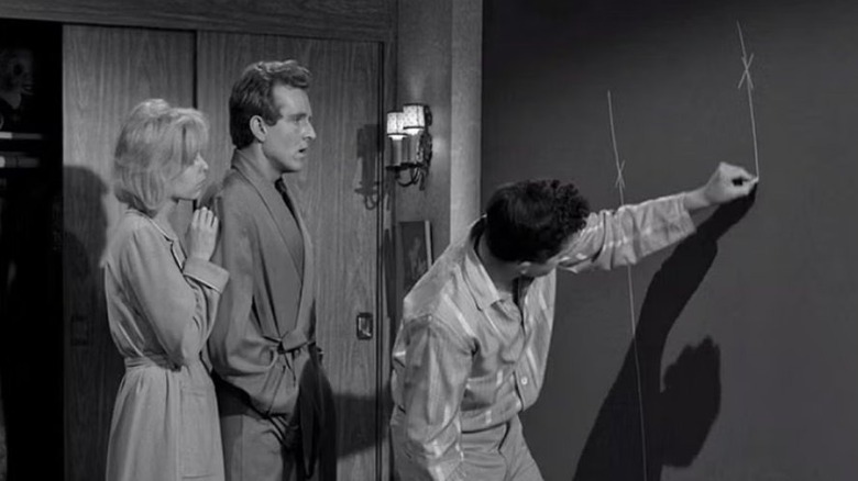 Ruth and Chris Miller watch their physicist friend, Bill, write on their wall in the The Twilight Zone episode "Little Girl Lost"