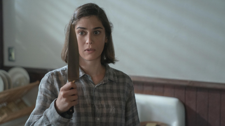Annie Wilkes holding a knife and looking at it