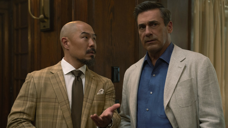 Hoon Lee as Barney Choi and Jon Hamm as Andrew Cooper in suits, shown side by side.