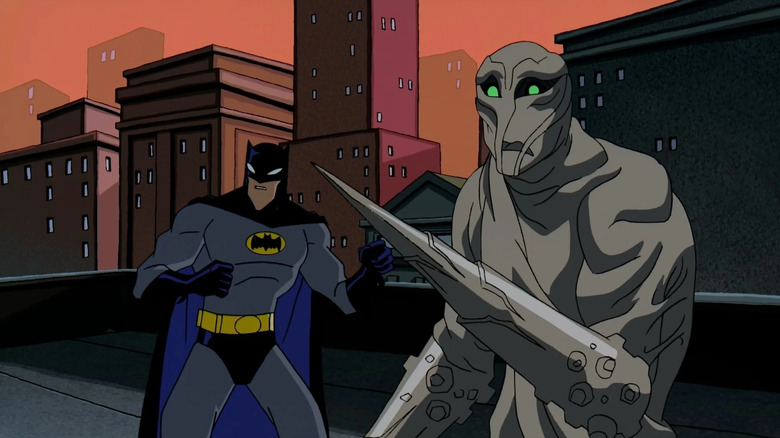 On the left is Batman wearing a gray suit with a black cape and white eyes. On the right is Clayface with green eyes and a spike where his left hand should be.
