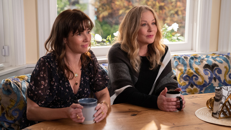 Linda Cardellini as Judy Hale and Christina Applegate as Jen Harding setting next to each other and holding mugs in "Dead to Me."
