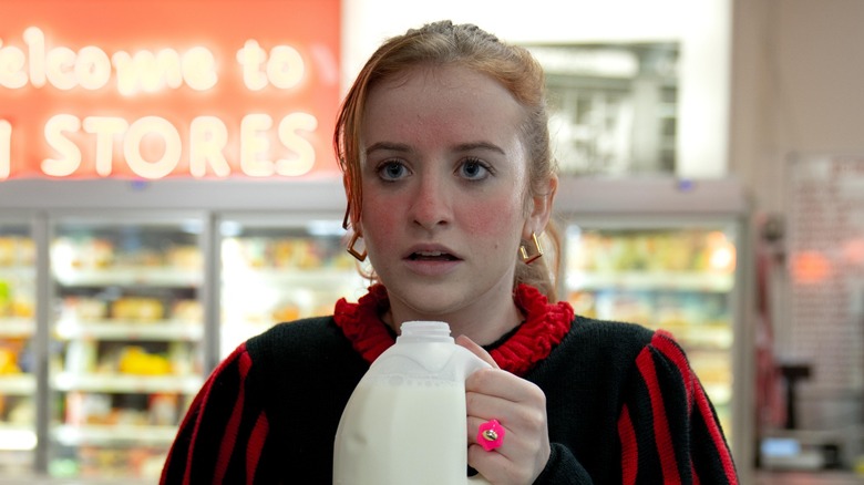 A red-in-the-face Jane holding a carton of milk in a supermarket in "Extraordinary."