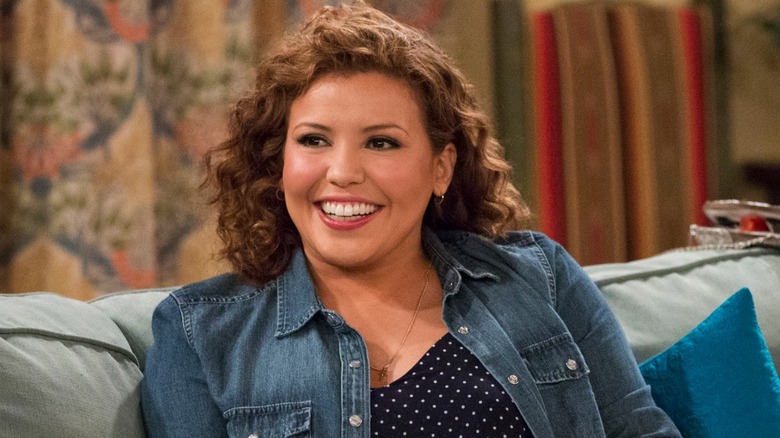 Penelope smiling on a sofa in "One Day at a Time"