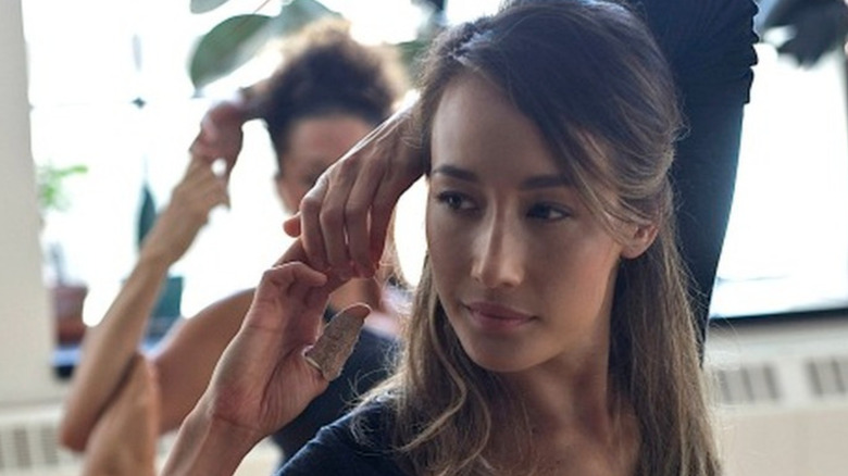 Maggie Q as Nikita, she has long brown hair and has bandages on some of her thumb.