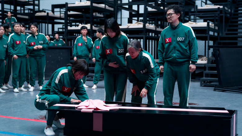 Player 120, Player 222, Player 149, and Player 007 all look worried at a black and pink casket
