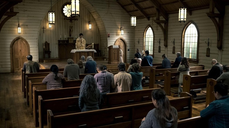 Father Paul Hill leading a group of townsfolk in prayer at a church