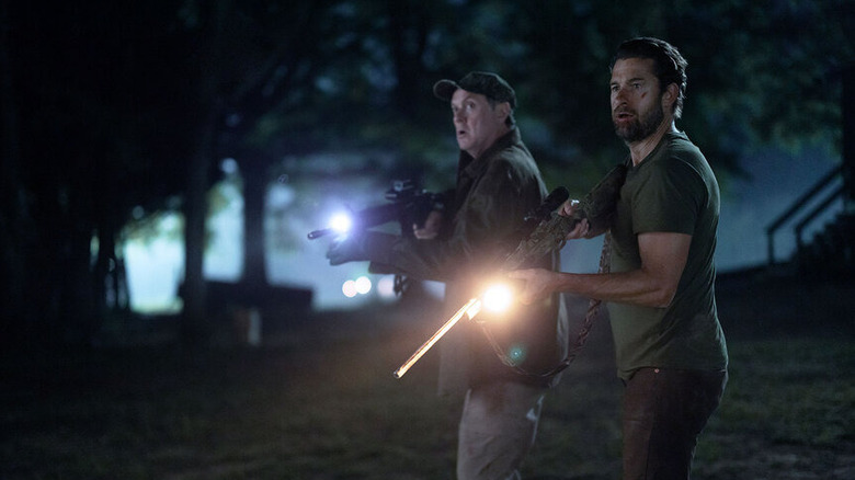 Donald Kelly and James Chenoweth outside holding guns and looking on