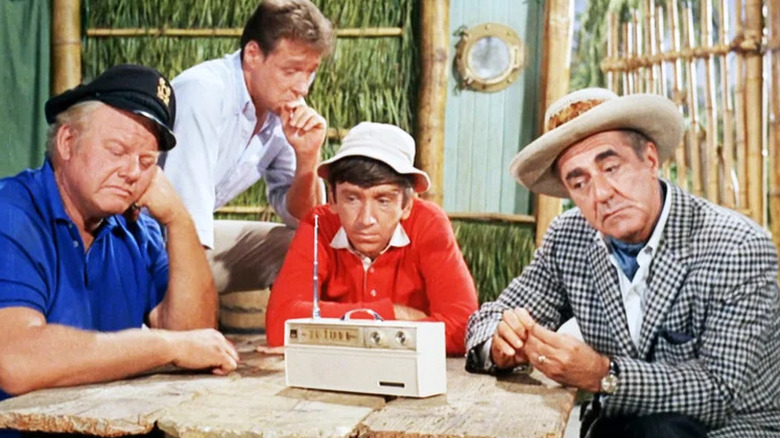 Alan Hale Jr. as The Skipper, Russell Johnson as The Professor, Bob Denver as Gilligan, and Jim Backus as Thurston Howell III sitting around radio in Gilligan's Island