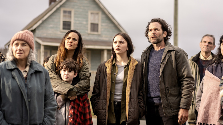 The Matthews family standing in front of a house looking at something in the distance in From