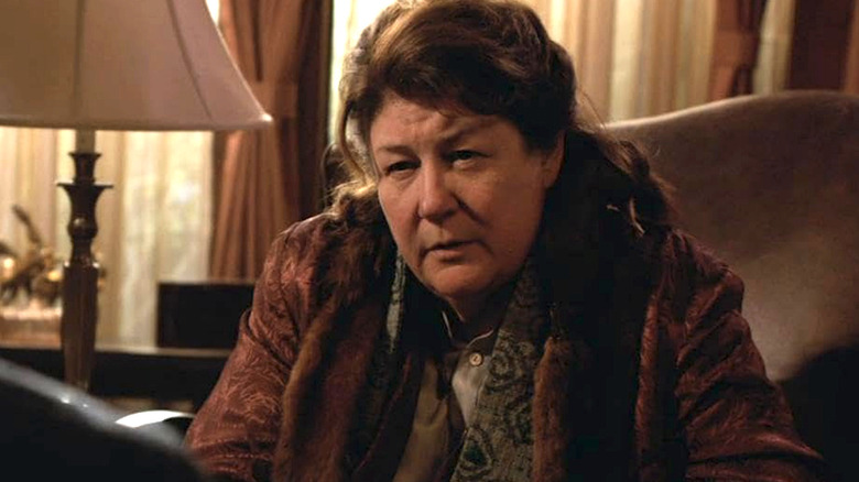 Mags Bennett Justified'da kahverengi ceketiyle oturuyor