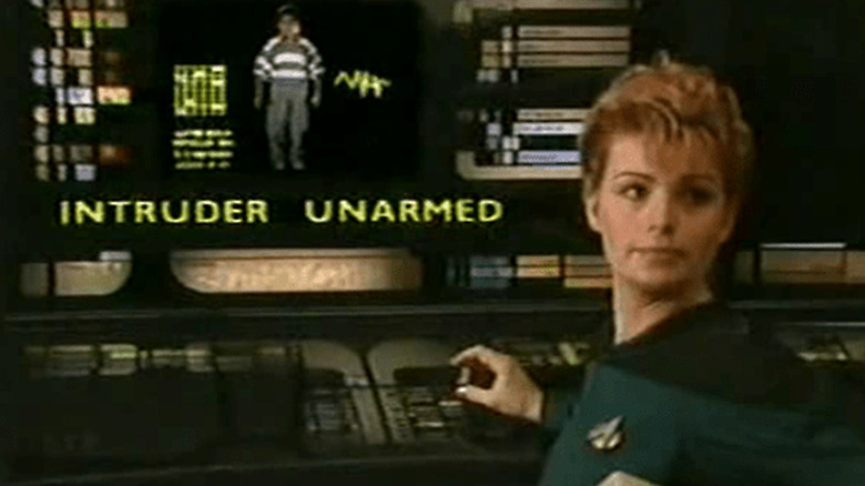 An Enterprise crew member turns from a screen confirming Webster Long is unarmed