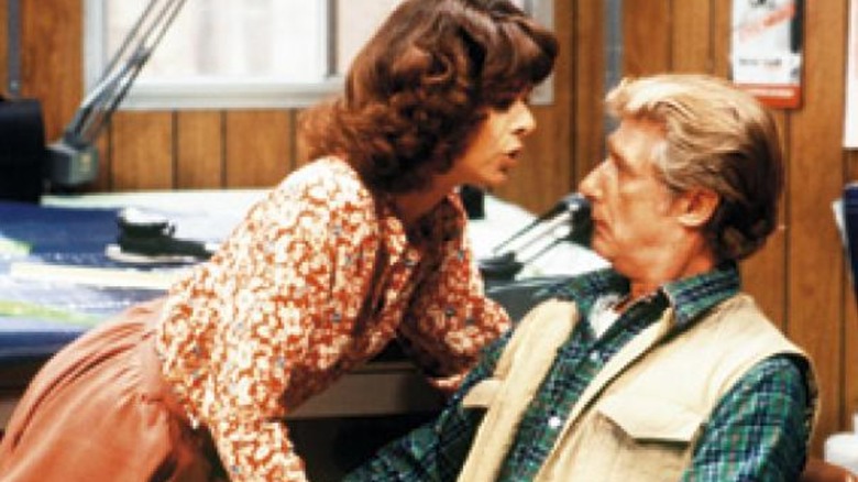 Burt Campbell observes in vest as a woman leans over him on "Soap"