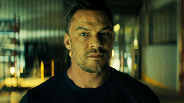 Alan Ritchson's Jack Reacher is seen in closeup as he stands in a warehouse in Reacher