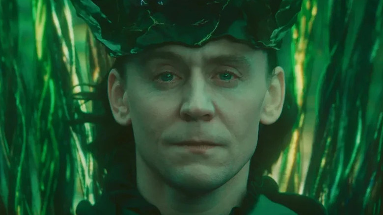 Tom Hiddleston's Loki looking conflicted against a glowing green backdrop on Loki