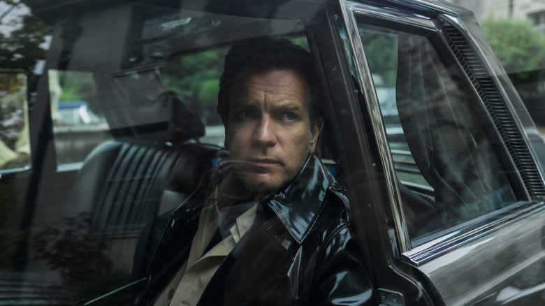 Ewan McGregor's Halston wearing a shiny black coat in a car on Halston