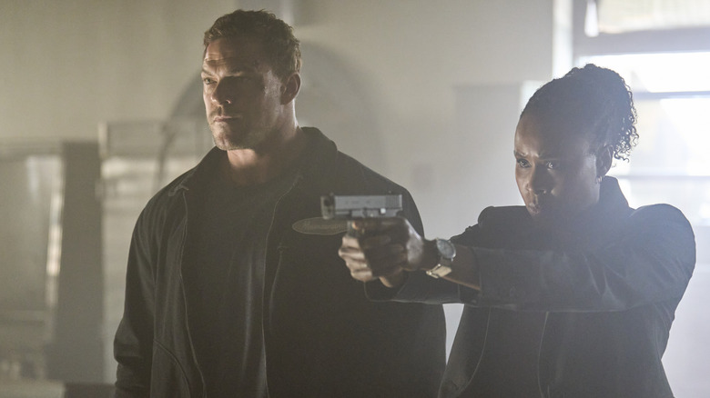 Tamara Green aiming a pistol while standing beside Jack Reacher in 
